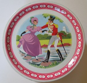 The Quality Street Soldier helps the Lady across the stepping stones